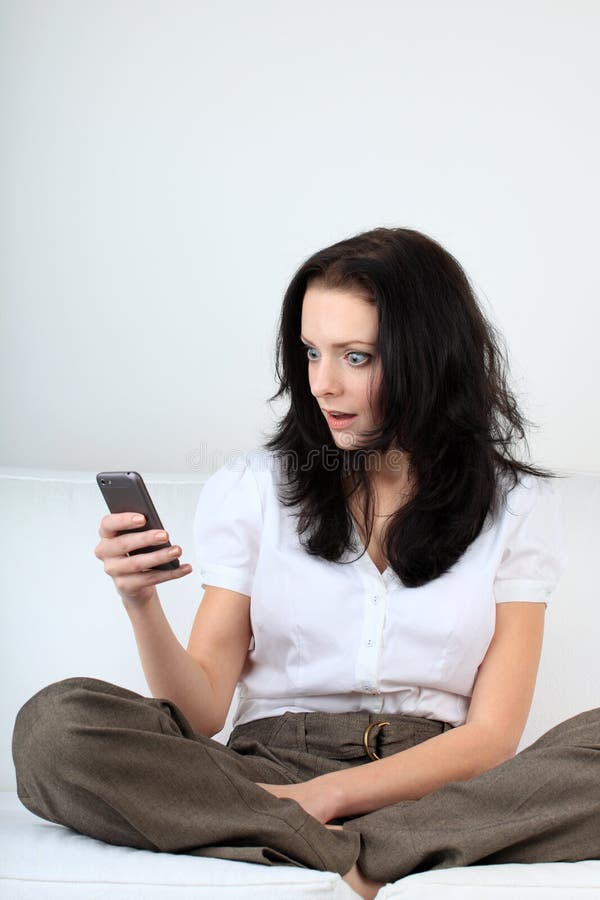 Jeune femme avec l'expression heureuse regardant le message à son téléphone portable photo libre de droits Jeune femme avec l'expression heureuse regardant le message à son téléphone portable photo libre de droits