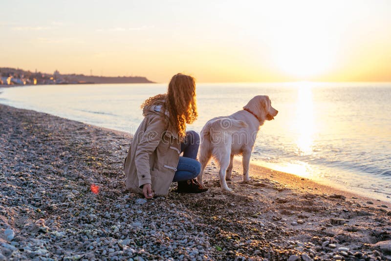 Jeune femme avec le golden retriever sur la plage photo libre de droits Jeune femme avec le golden retriever sur la plage photo libre de droits