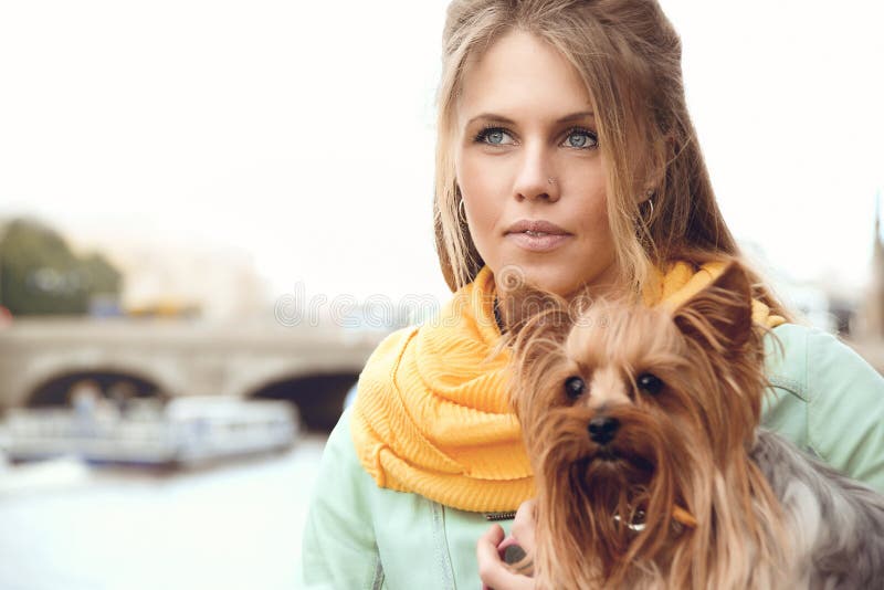 Jeune femme avec le petit chien sur l'embarkment, amie de attente image stock Jeune femme avec le petit chien sur l'embarkment, amie de attente image stock