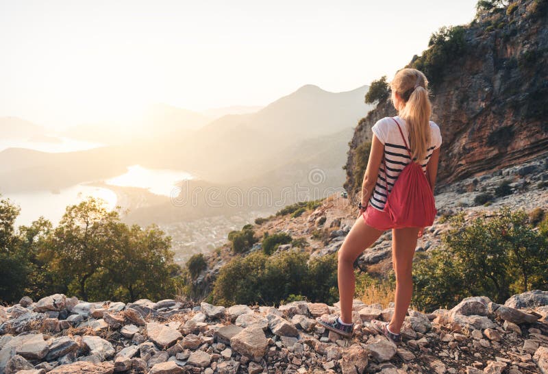 Jeune femme avec le sac à dos se tenant sur la colline photographie stock libre de droits Jeune femme avec le sac à dos se tenant sur la colline photographie stock libre de droits