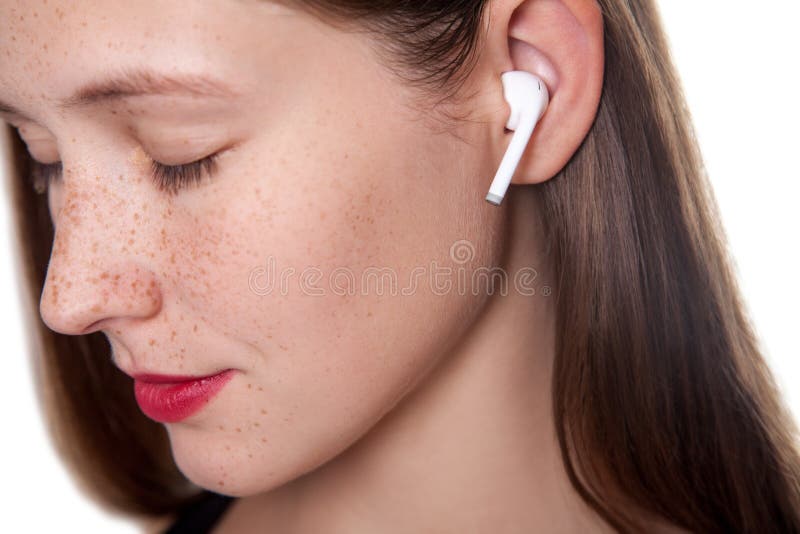 Jeune femme avec les écouteurs sans fil photographie stock libre de droits Jeune femme avec les écouteurs sans fil photographie stock libre de droits
