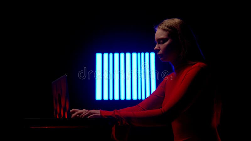 Jeune femme avec ordinateur portable contre mur numérique dans le club sombre. silhouette femme assise dactylographie sur ordinate banque de vidéos