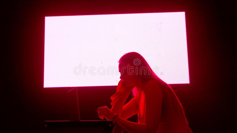 Jeune femme avec ordinateur portable contre mur numérique dans le club sombre. femme silhouette assise surfs sur ordinateur portab banque de vidéos