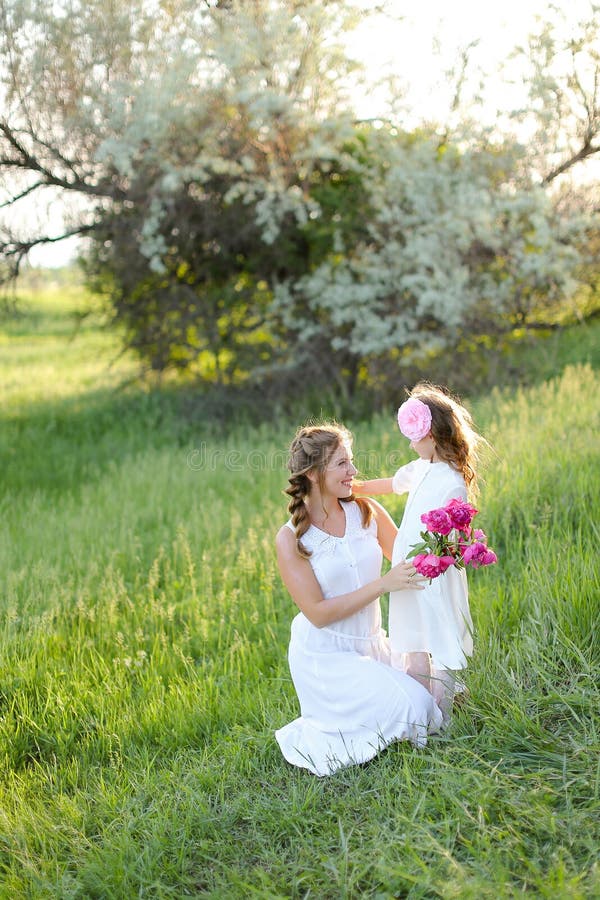 Jeune femme blonde assise avec petite fille sur l'herbe. photo stock