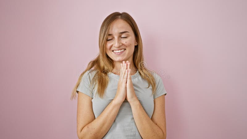 Jeune femme blonde confiante sourit joyeusement debout décontracté avec les mains ensemble rayonnant positivité sur un rose isolé clips vidéos