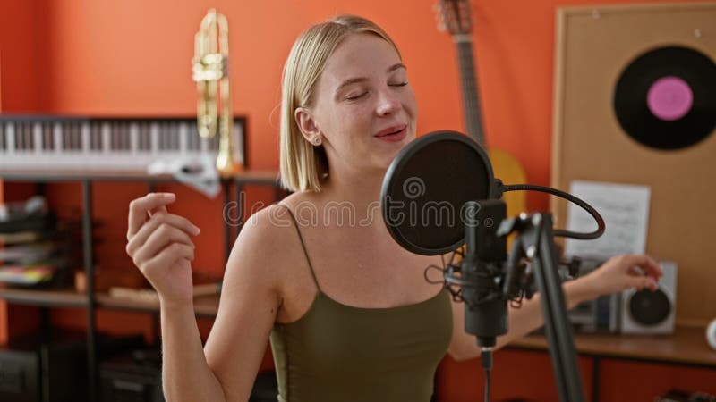 Jeune femme blonde musicienne chantant chanson dansant au studio de musique