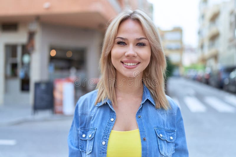 Jeune femme blonde souriante confiante debout dans la rue photographie stock