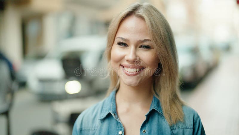 Jeune femme blonde souriante confiante debout dans la rue image libre de droits
