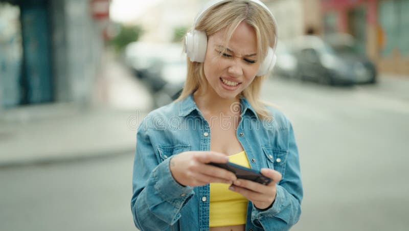 Jeune femme blonde souriante confiante jouer à un jeu vidéo dans la rue image libre de droits