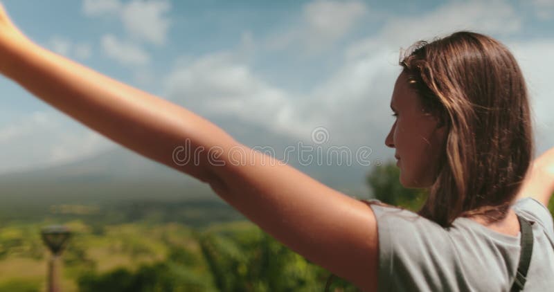 Jeune femme brandissant des armes admirant la vue tropicale du volcan mayon banque de vidéos