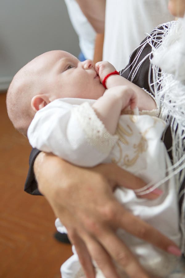 Jeune femme caucasienne de mère tenant le petit enfant infantile dans le bapt photo stock Jeune femme caucasienne de mère tenant le petit enfant infantile dans le bapt photo stock