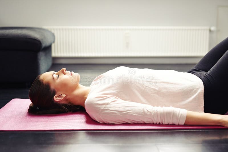 Jeune femme convenable détendant sur le tapis de yoga