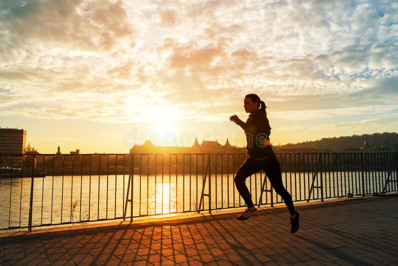 Jeune femme courant dans le coucher du soleil photo libre de droits Jeune femme courant dans le coucher du soleil photo libre de droits
