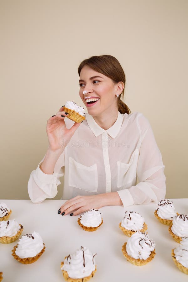Jeune femme d'une manière amusante heureuse souriant et mangeant des gâteaux image libre de droits