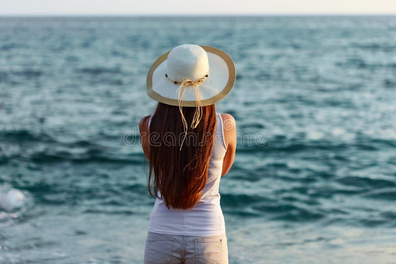 Jeune femme dans l'équipement et le chapeau d'été par le bord de la mer images stock Jeune femme dans l'équipement et le chapeau d'été par le bord de la mer images stock