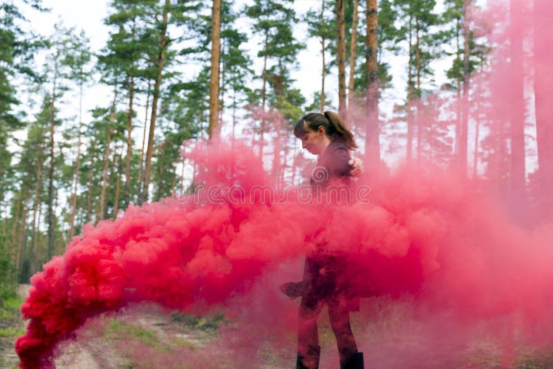 Jeune femme dans la forêt ayant l'amusement avec la grenade fumigène rouge, bombe photos libres de droits Jeune femme dans la forêt ayant l'amusement avec la grenade fumigène rouge, bombe photos libres de droits
