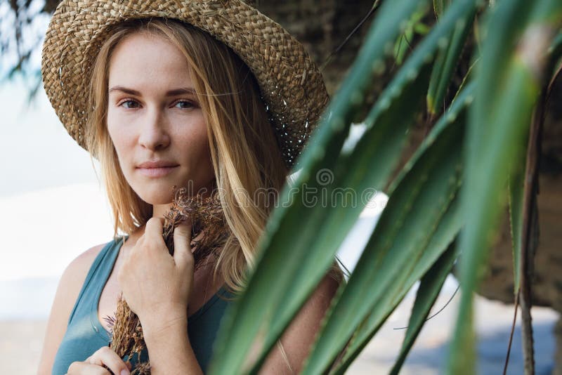 Jeune femme dans le bouquet de prise de chapeau de paille des wildflowers secs photographie stock libre de droits Jeune femme dans le bouquet de prise de chapeau de paille des wildflowers secs photographie stock libre de droits