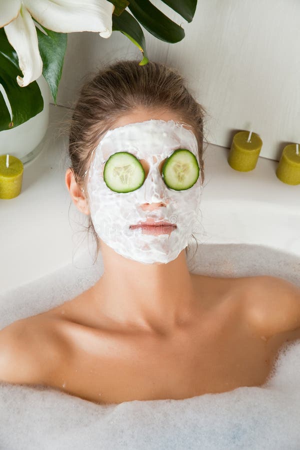 Young beauty woman in the bath with face mask and cucumber. Young beauty woman in the bath with face mask and cucumber