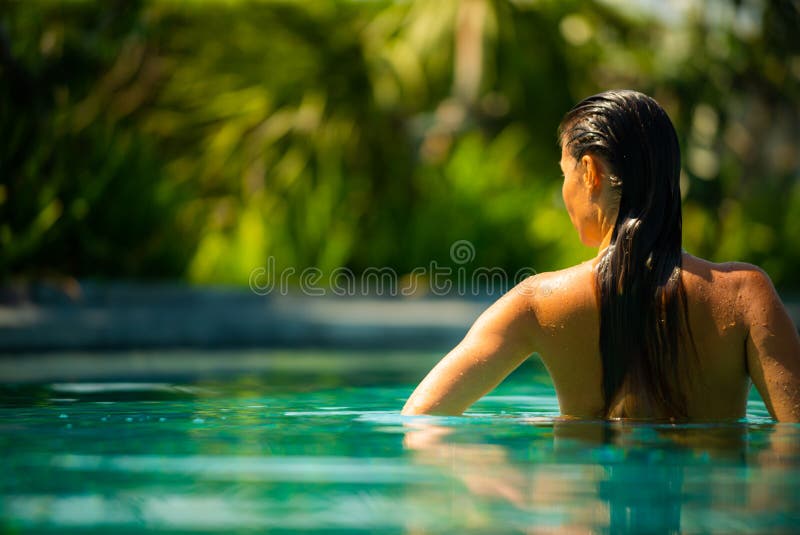 Jeune femme de brune détendant par le côté de la piscine d'infini images libres de droits Jeune femme de brune détendant par le côté de la piscine d'infini images libres de droits