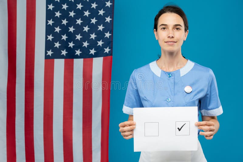Jeune femme de chambre brune en uniforme bleu montrant son bulletin de vote photographie stock libre de droits