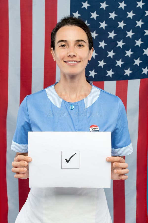 Jeune femme de chambre de sourire contemporaine en uniforme pour vous montrer son bulletin de vote image libre de droits