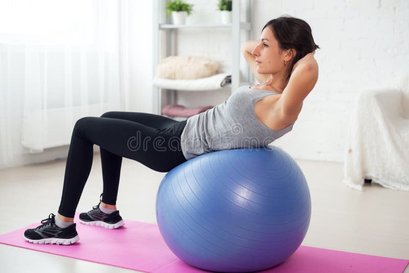 Jeune femme de forme physique faisant des craquements abdominaux sur la boule d'ajustement image stock Jeune femme de forme physique faisant des craquements abdominaux sur la boule d'ajustement image stock