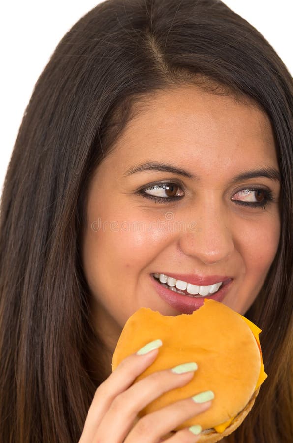 Jeune femme de headshot de plan rapproché belle posant pour l'appareil-photo mangeant l'hamburger tout en souriant heureusement, image libre de droits Jeune femme de headshot de plan rapproché belle posant pour l'appareil-photo mangeant l'hamburger tout en souriant heureusement, image libre de droits