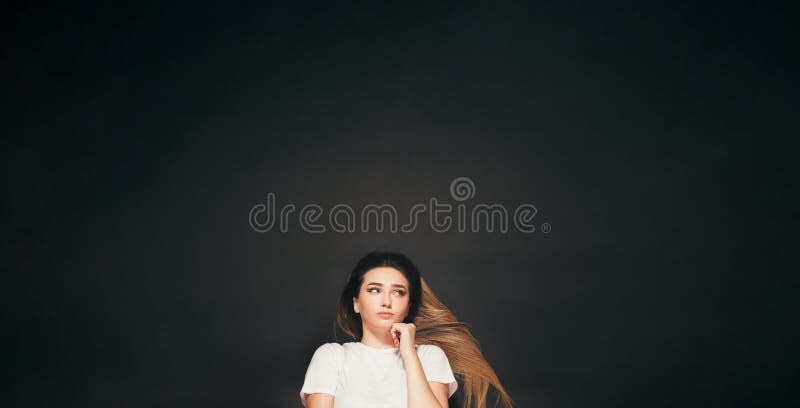 Jeune femme de pensée avec de longs cheveux se trouvant sur la vue de dessus de fille confuse de fond de studio photo stock