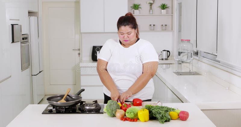 Jeune femme de poids excessif préparant des légumes banque de vidéos