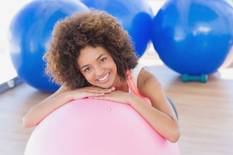 Jeune femme de sourire avec la boule de forme physique au gymnase images stock Jeune femme de sourire avec la boule de forme physique au gymnase images stock