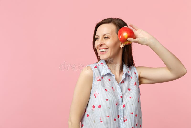 Jeune femme de sourire dans des vêtements d'été regardant de côté jugeants le fruit rouge mûr frais de pomme d'isolement sur le p image libre de droits Jeune femme de sourire dans des vêtements d'été regardant de côté jugeants le fruit rouge mûr frais de pomme d'isolement sur le p image libre de droits