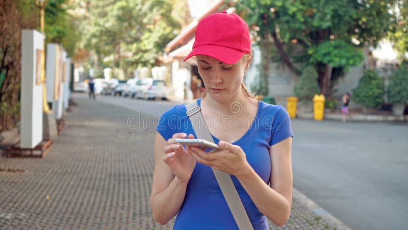 Jeune femme de touristes attirante dans le chapeau rouge utilisant la carte en ligne dans le smartphone pour les bonnes direction clips vidéos
