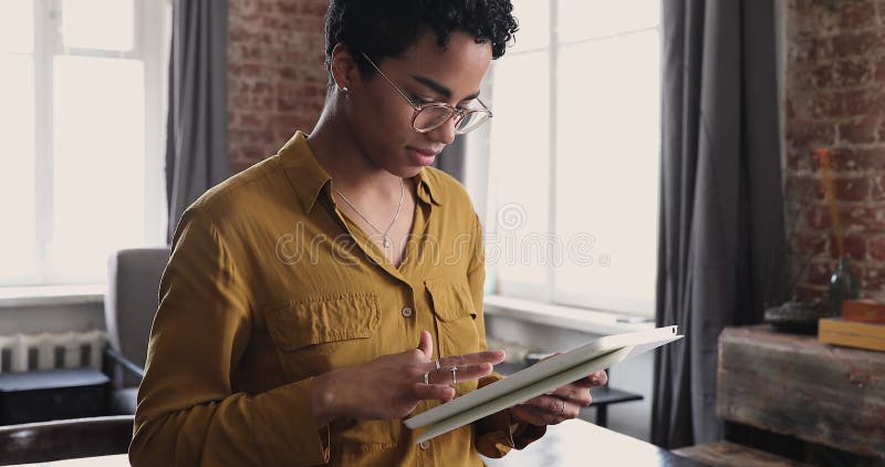 Jeune femme designer africaine stand by table working on tablet banque de vidéos