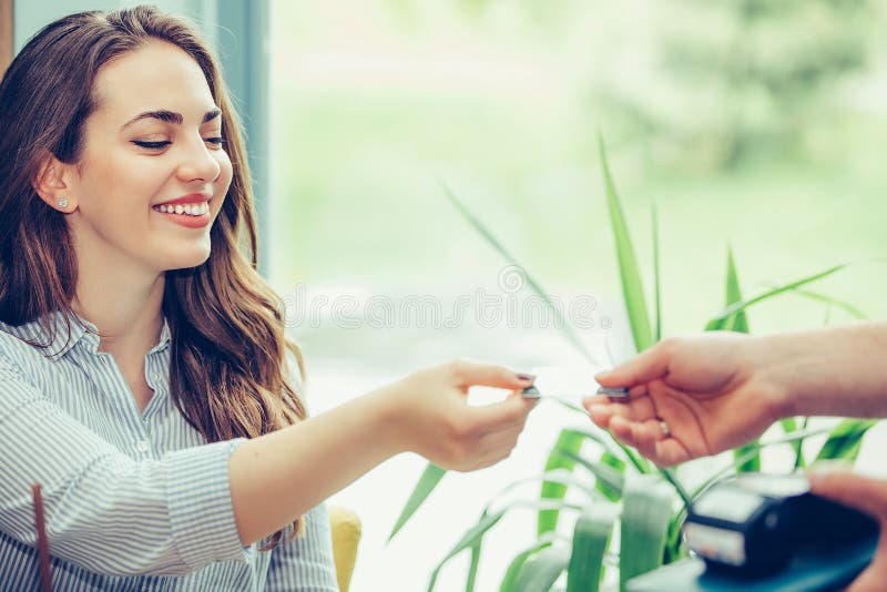 Jeune femme donnant la carte de crédit à la main de serveur et payant le café au café photographie stock libre de droits Jeune femme donnant la carte de crédit à la main de serveur et payant le café au café photographie stock libre de droits