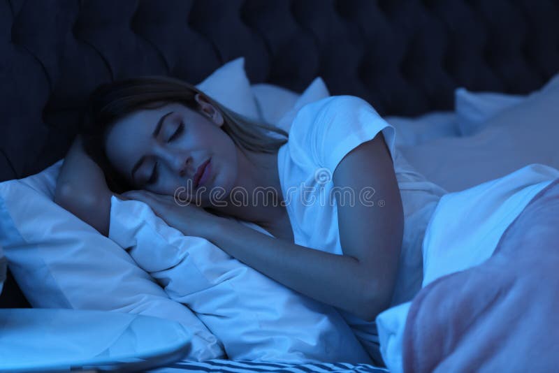 Jeune femme dormant dans le lit la nuit photos stock Jeune femme dormant dans le lit la nuit photos stock
