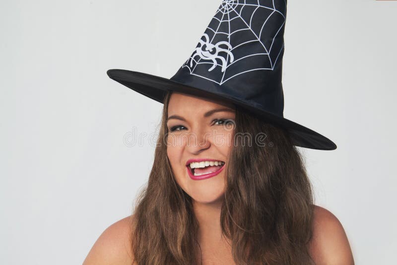 Funny young smiling woman wearing Halloween witch hat on a white background. Funny young smiling woman wearing Halloween witch hat on a white background