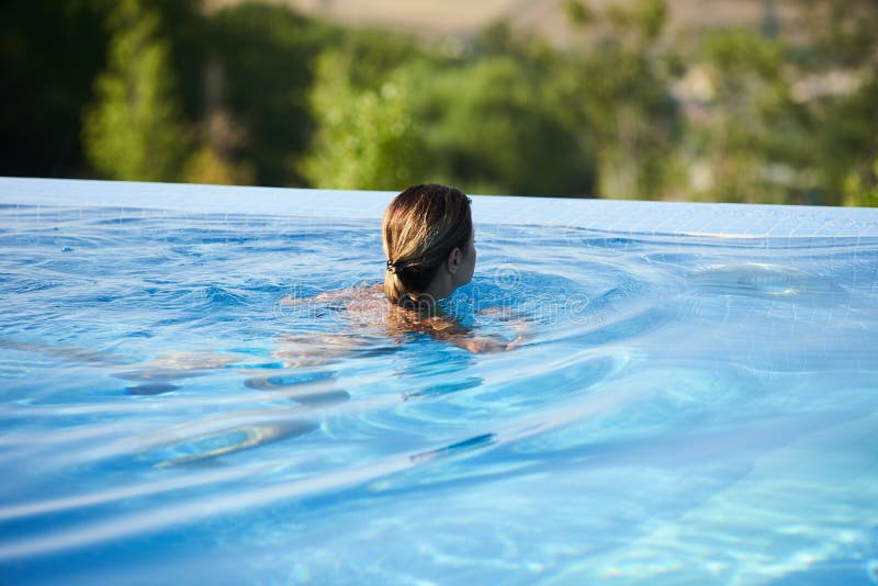 Jeune femme détendant dans la piscine d'infini images libres de droits Jeune femme détendant dans la piscine d'infini images libres de droits