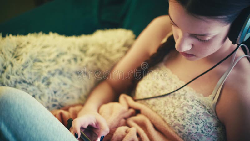 Jeune femme détendue profitant du temps de l'écran dans une ambiance cosy banque de vidéos