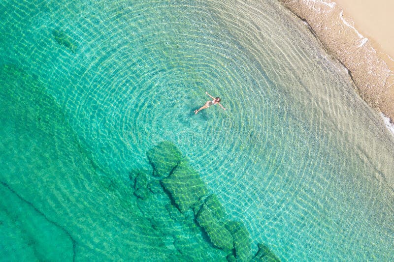 Jeune femme en bikini nageant dans l'eau de mer sur la plage. vue depuis le haut. vue de drone supérieure. image libre de droits