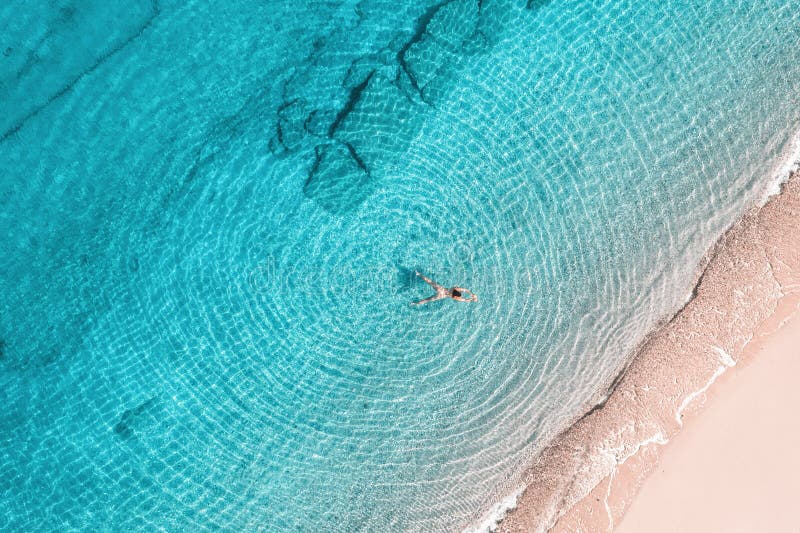 Jeune femme en bikini nageant dans l'eau de mer sur la plage. vue depuis le haut. vue de drone supérieure. images stock