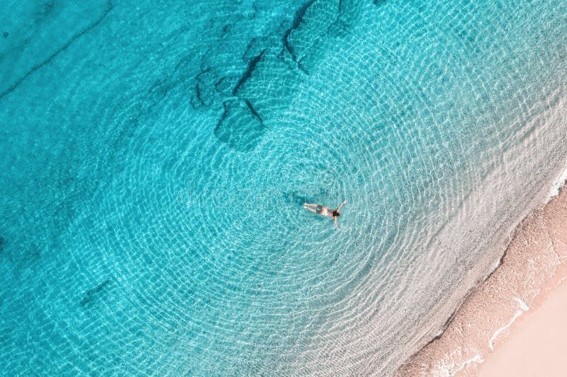 Jeune femme en bikini nageant dans l'eau de mer sur la plage. vue depuis le haut. vue de drone supérieure. image stock