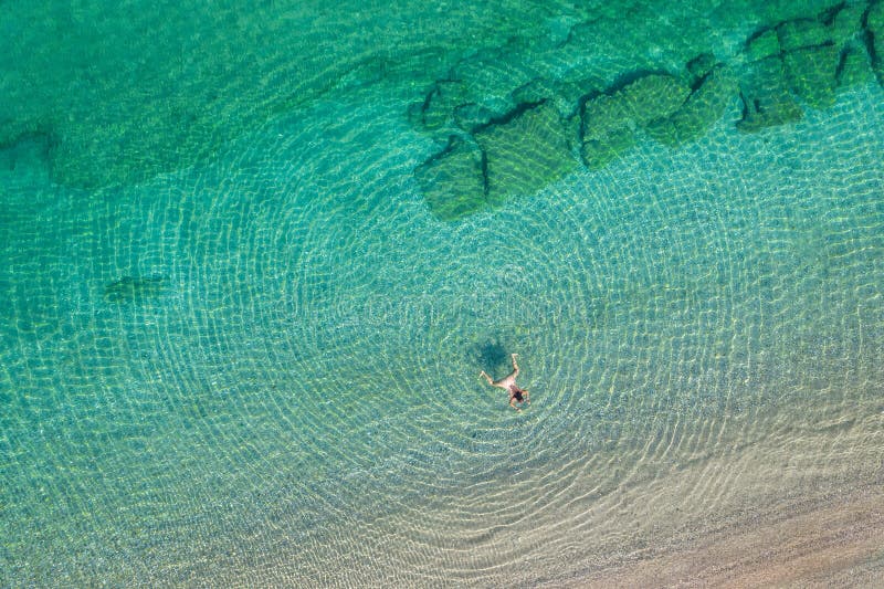 Jeune femme en bikini nageant dans l'eau de mer sur la plage. vue depuis le haut. vue de drone supérieure. image stock