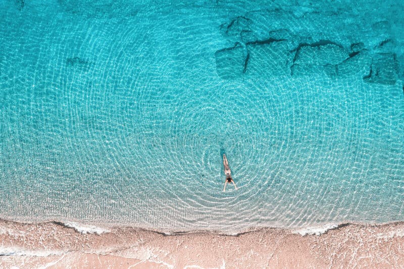 Jeune femme en bikini nageant dans l'eau de mer sur la plage. vue depuis le haut. vue de drone supérieure. images libres de droits