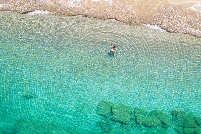 Jeune femme en bikini nageant dans l'eau de mer sur la plage. vue depuis le haut. vue de drone supérieure. photos stock