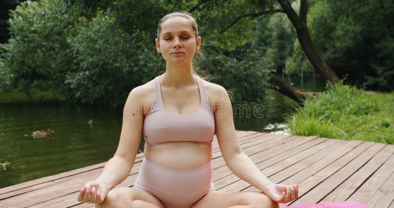 Jeune femme enceinte méditant dans la nature pratique yoga. soins de santé et grossesse banque de vidéos