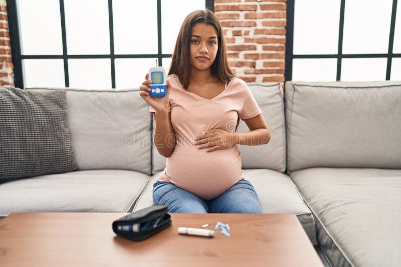 Jeune femme enceinte vérifiant la glycémie détendue avec une expression sérieuse sur le visage photo libre de droits