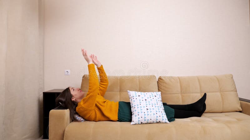 Jeune femme ennuyée dans le pull gît sur le canapé jetant des oreillers clips vidéos