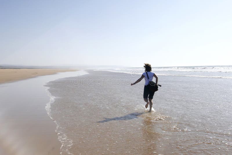 Jeune femme exécutant heureusement sur une plage images libres de droits Jeune femme exécutant heureusement sur une plage images libres de droits