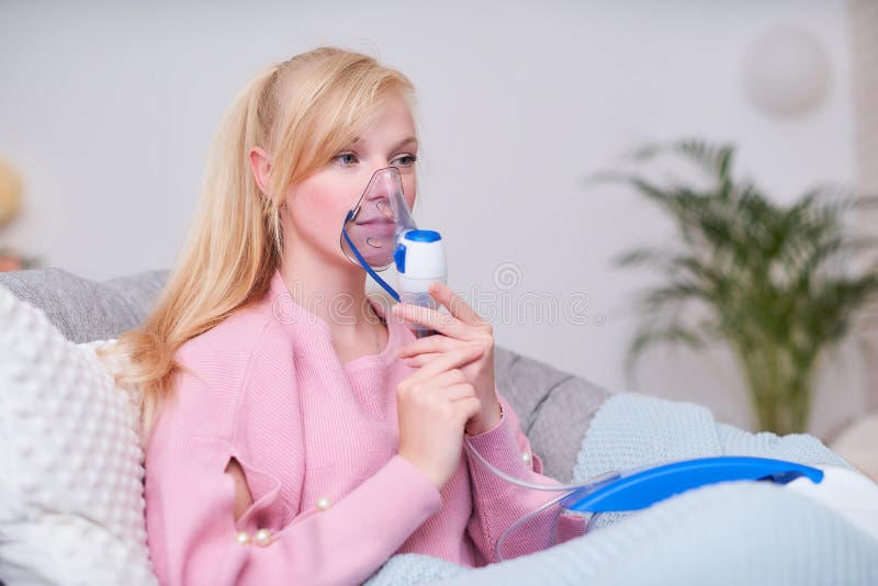 Jeune femme faisant l'inhalation avec un n?buliseur ? la maison image libre de droits Jeune femme faisant l'inhalation avec un n?buliseur ? la maison image libre de droits