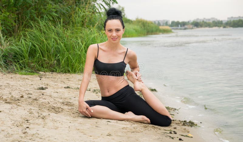 Jeune femme faisant le yoga sur la berge Séjour en ville photos stock Jeune femme faisant le yoga sur la berge Séjour en ville photos stock